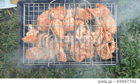 Beef cooked in an outdoor coal barbecue. Barbecue on a metal grill on hot coals. 69997742