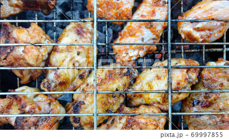 Chicken wings on barbecue grill with fire close up. Chicken meat on the grill 69997855