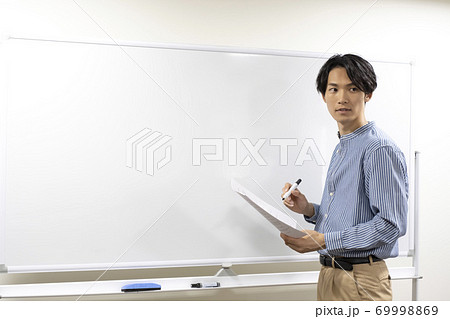 ホワイトボードに書こうとしている若い男性(塾講師) ホワイトボードに書こうとしている若い男性(塾講師) 69998869