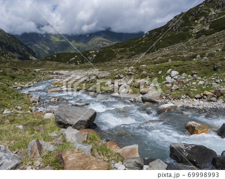 Summer view of alpine landscape with snow-capped mountain peaks and wild Freigerbach stream. Tyrol, Stubai Alps, Austria Summer view of alpine landscape with snow-capped mountain peaks and wild Freigerbach stream. Tyrol, Stubai Alps, Austria 69998993
