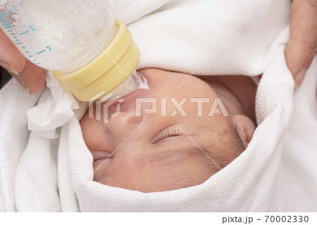 Newborn baby eating milk from small plastic milk 70002330