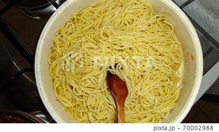 A large bowl with freshly cooked spaghetti and wooden spoon closeup A large bowl with freshly cooked spaghetti and wooden spoon closeup 70002988