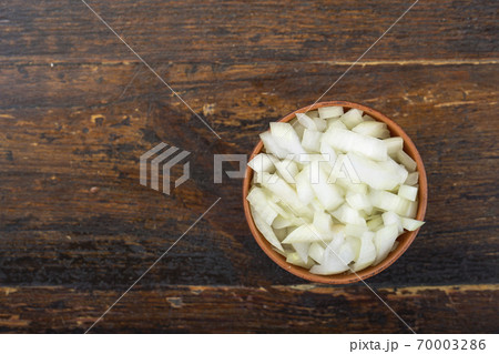 Sliced raw onion in a bowl on a wooden background. Vegetable, ingredient and staple food. 70003286