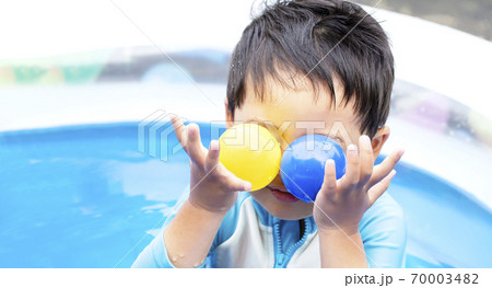外で水遊びで大はしゃぎしている子供　青と黄色のボールを2つ目の前に持っている子供 70003482