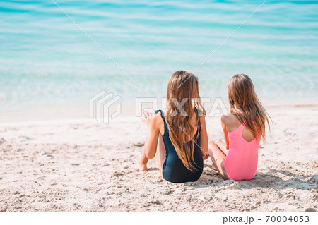 Two little happy girls have a lot of fun at tropical beach playing