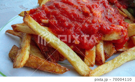 french fries covered with hot organic  tomato sauce closeup in the white plate french fries covered with hot organic  tomato sauce closeup in the white plate 70004110