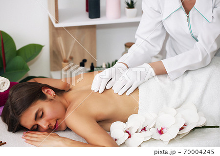back massage.Young beautiful european woman sleeping relaxing on oil spa massage in salon. 70004245