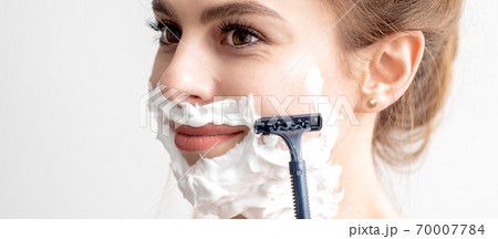 Woman shaving her face by razor 70007784