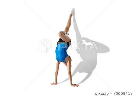 Beautiful young female athlete stretching on white studio background with shadows Beautiful young female athlete stretching on white studio background with shadows 70008415