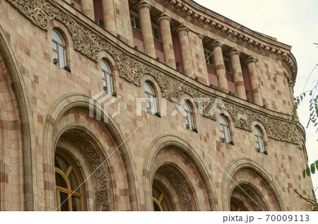 The corner of the building on the square in Yerevan is built of colored stone, with loggias, columns, arches and beautiful edging of ethnic decor on the facade The corner of the building on the square in Yerevan is built of colored stone, with loggias, columns, arches and beautiful edging of ethnic decor on the facade 70009113