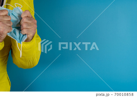 man in yellow jacket is using a protective mask against corona virus on blue background 70010858