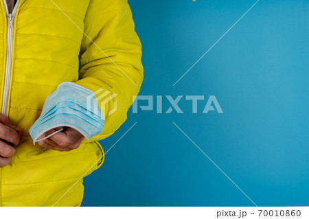 man in yellow jacket is using a protective mask against corona virus on blue background 70010860