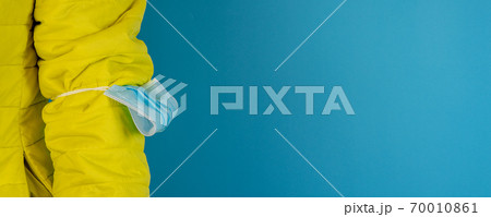 man in yellow jacket is using a protective mask against corona virus on blue background 70010861