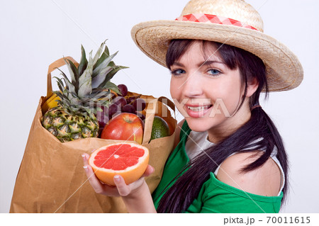 A young woman shows fruits from a shopping bags 70011615