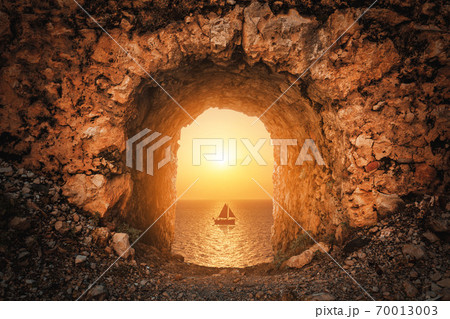 A nice view from a antique historical castle to the sea with a sailboat against sunset. 70013003