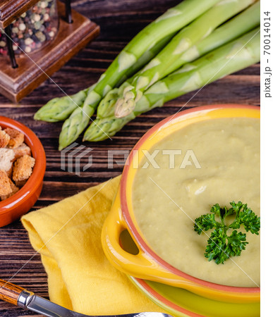 Fresh asparagus creamy soup and ingredients on a wooden table. 70014014