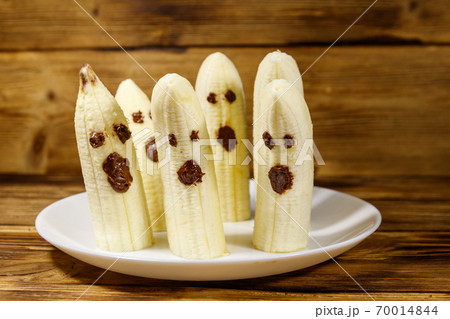 Homemade Halloween scary banana ghosts monsters with chocolate faces. Funny dessert for Halloween party on wooden table Homemade Halloween scary banana ghosts monsters with chocolate faces. Funny dessert for Halloween party on wooden table 70014844