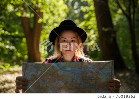 young caucasian woman in a hat looking at a geographic map  70019362