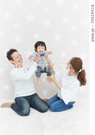 赤ちゃんをパパとママが高い高いしている親子写真の写真素材