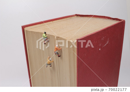 a mini of figures climb, conquer a big book. a mini of figures climb, conquer a big book. 70022177