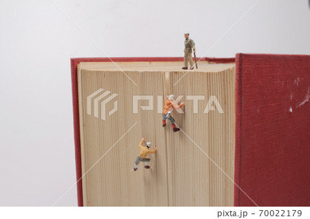 a mini of figures climb, conquer a big book. 70022179
