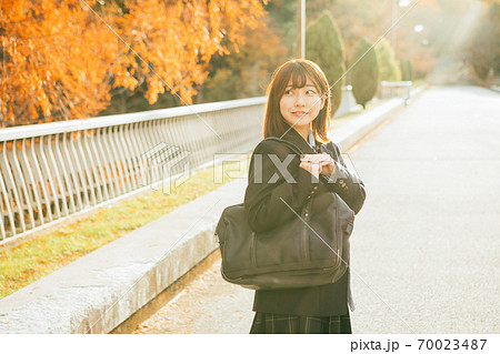 紅葉した街を歩く女子高生 70023487