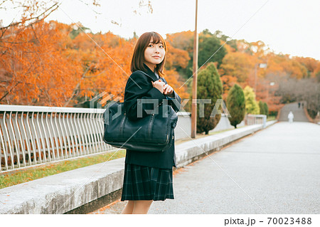 紅葉した街を歩く女子高生 70023488