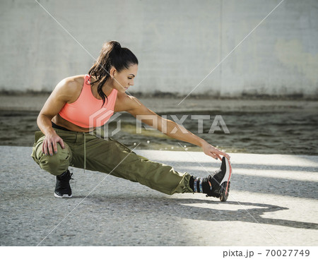 Sporty woman stretching outdoors Sporty woman stretching outdoors 70027749