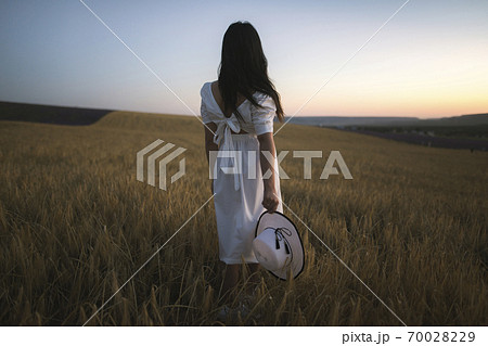 France, Woman in white dress standing in field 70028229