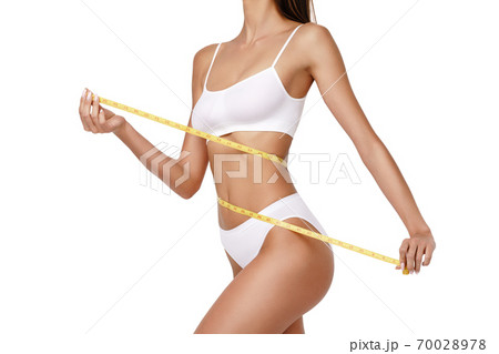 Slim tanned woman's body over gray background - waist measurement 70028978