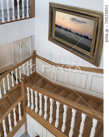 Stairwell in a house with traditional wooden bannisters and oil painting on wall 70029901