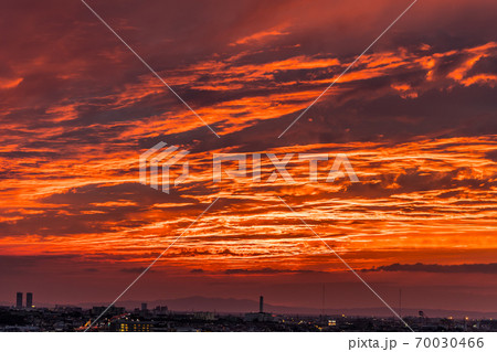 空を覆う雲に照らし出される赤い夕焼けの写真素材