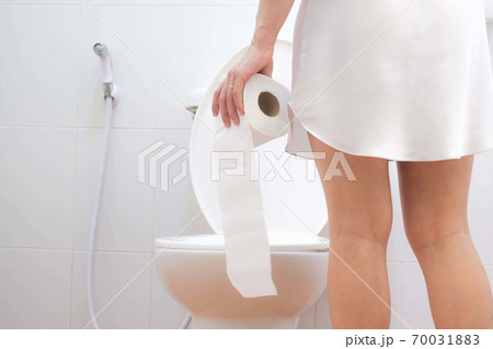 Women wearing white sleepwear, Sitting on the toilet Hand holding the stomach,standing in the toilet, Holding a toilet paper, bent, stomachache health care concept 70031883