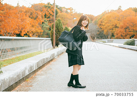 紅葉した街を歩く女子高生 70033755