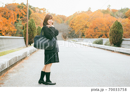 紅葉した街を歩く女子高生 70033758