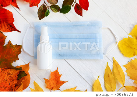 Mockup of white plastic spray bottle, Medical protective blue face mask and autumn bright colorful leaves on a white wooden table. Top view, mockup, flatlay. Biological concept of life in new reality Mockup of white plastic spray bottle, Medical protective blue face mask and autumn bright colorful leaves on a white wooden table. Top view, mockup, flatlay. Biological concept of life in new reality 70036573
