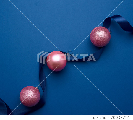 silk ribbon and pink shiny Christmas balls on a blue background 70037714