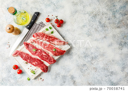 Raw steak with spices on wooden cutting board 70038741