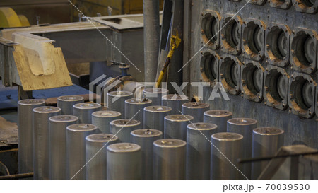 Forming aluminum column after melting in modern factory. Production of aluminium metal profiles, commonly used as material in construction and manufacturing. Forming aluminum column after melting in modern factory. Production of aluminium metal profiles, commonly used as material in construction and manufacturing. 70039530