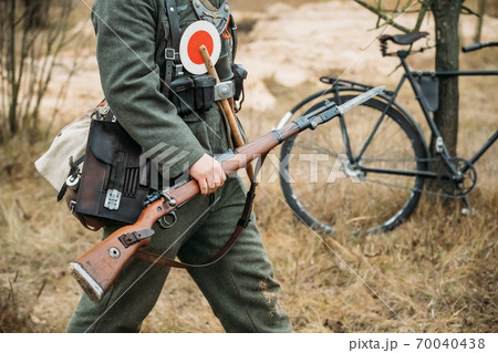 Re-enactor Dressed As World War II German Soldier Feldgendarm Holding Rifle. Soldier Holding Weapon. German Military Ammunition Of A German WW2 Soldier Re-enactor Dressed As World War II German Soldier Feldgendarm Holding Rifle. Soldier Holding Weapon. German Military Ammunition Of A German WW2 Soldier 70040438