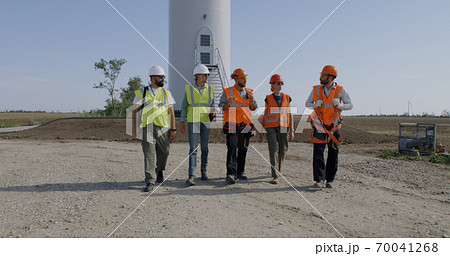Workers in masks walking near wind turbine 70041268
