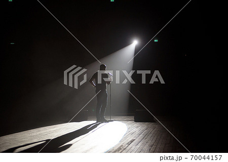 Stand up comedian on stage in the beam of light. Stand up comedian on stage in the beam of light. 70044157