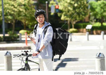 スマホを持つ自転車で配達をするデリバリーの男性 スマホを持つ自転車で配達をするデリバリーの男性 70045076