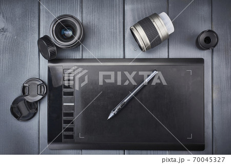 Graphic design tablet and pen with photographic lenses on gray wooden desk 70045327