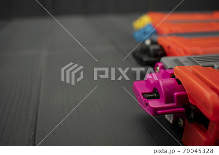 Toner cartridges in magenta, black, cyan and yellow colors on gray wooden background 70045328