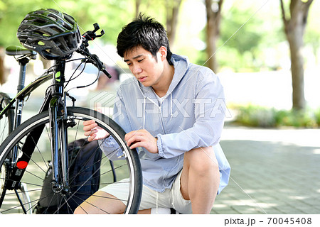 自転車のトラブルに困る若い男性 70045408