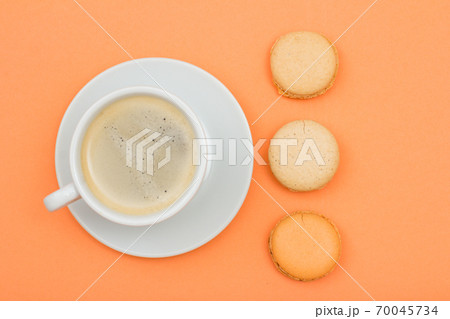 Cup of coffee and delicious macarons cakes on peach background 70045734