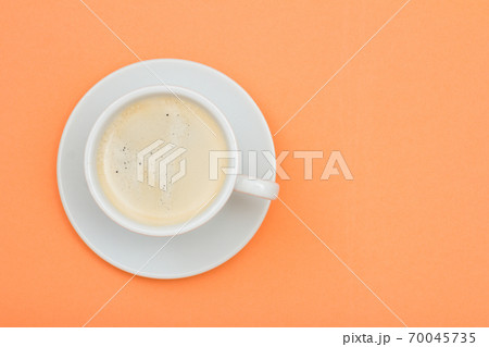 White porcelain cup of black coffee on saucer on peach color background 70045735