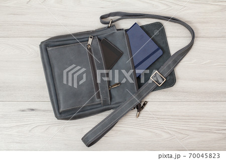 Leather shoulder bag for men with mobile phone and notebook on gray background 70045823