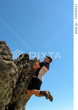 The man is engaged in mountaineering, climbs to the top, an epic view of the climber against the sky and mountains. 70046027
